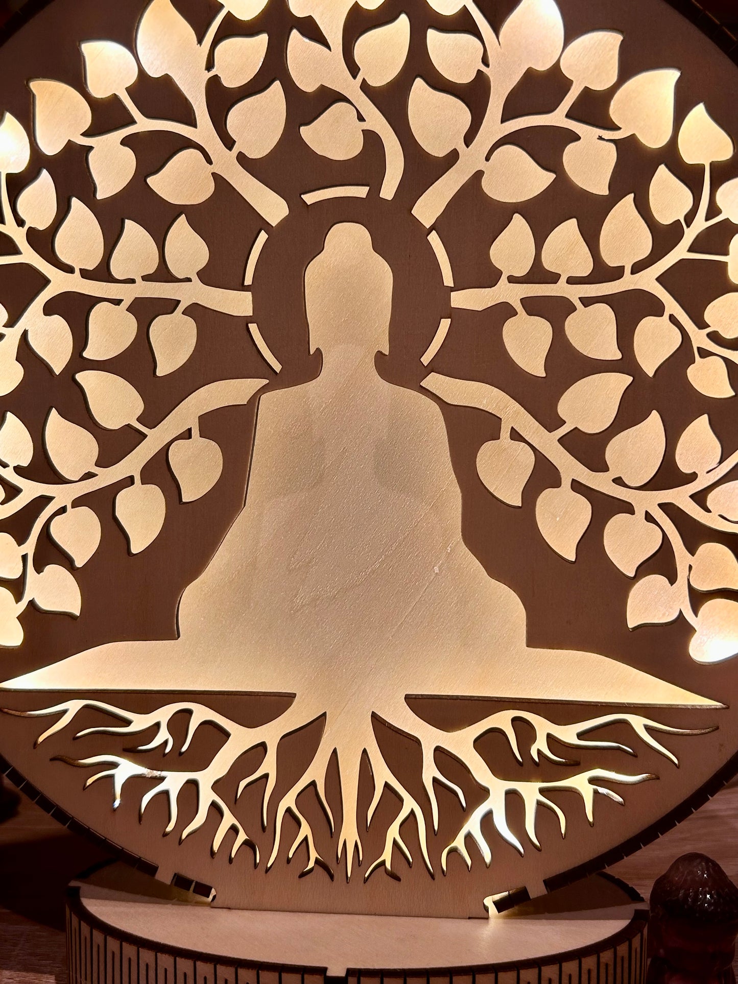 Silhouette lumineuse d’un bouddha au pied d’un arbre