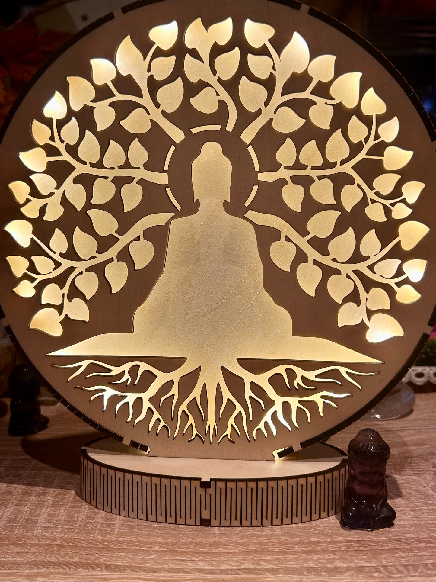 Silhouette lumineuse d’un bouddha au pied d’un arbre