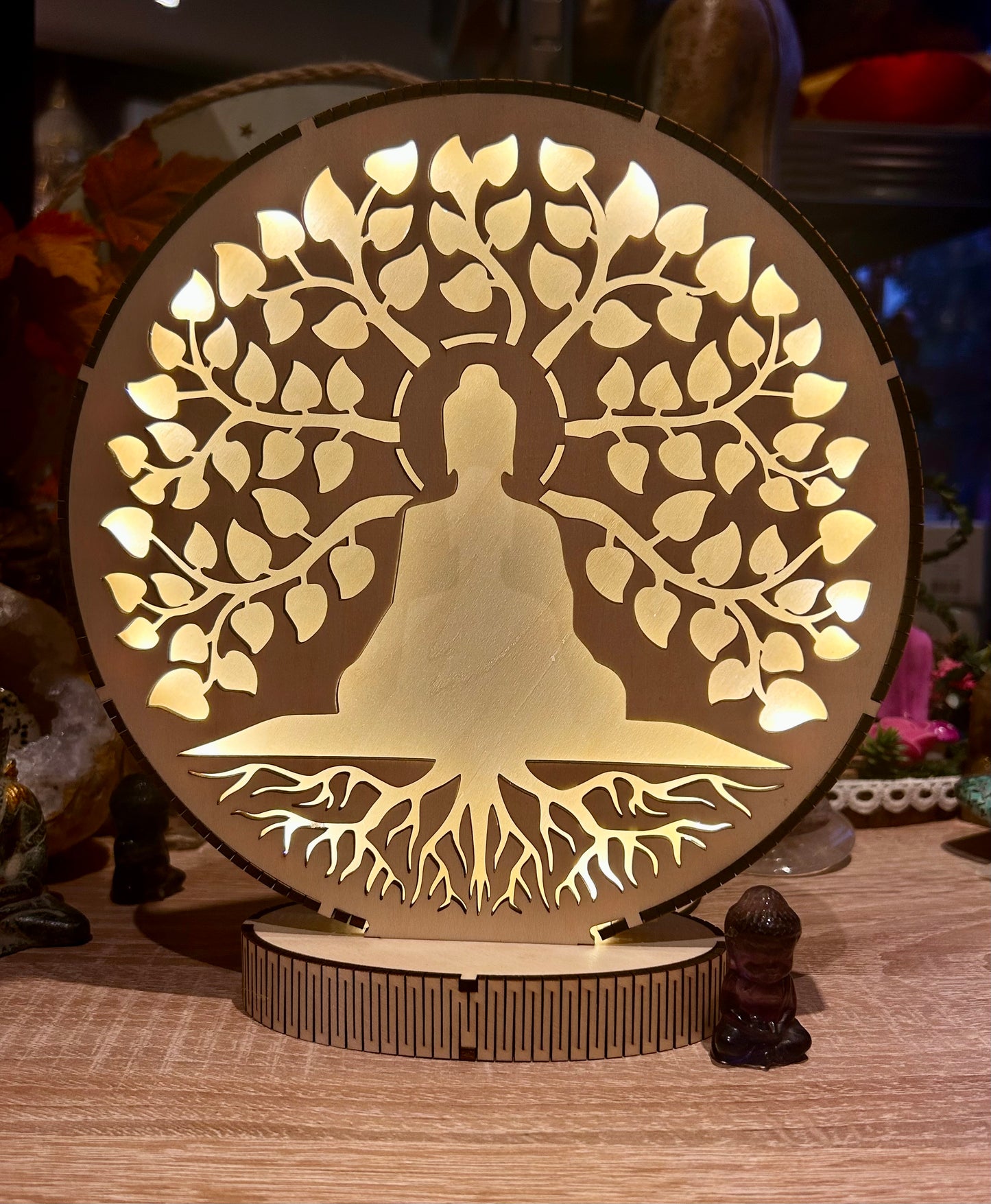 Silhouette lumineuse d’un bouddha au pied d’un arbre